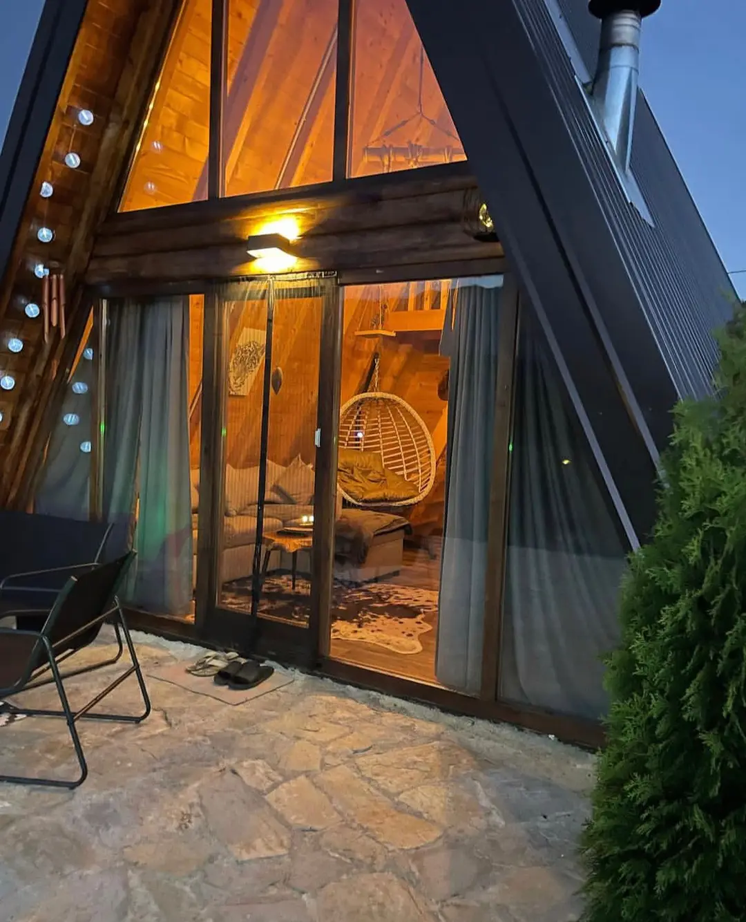 Entrance to an A-frame house through glass doors, lit at night