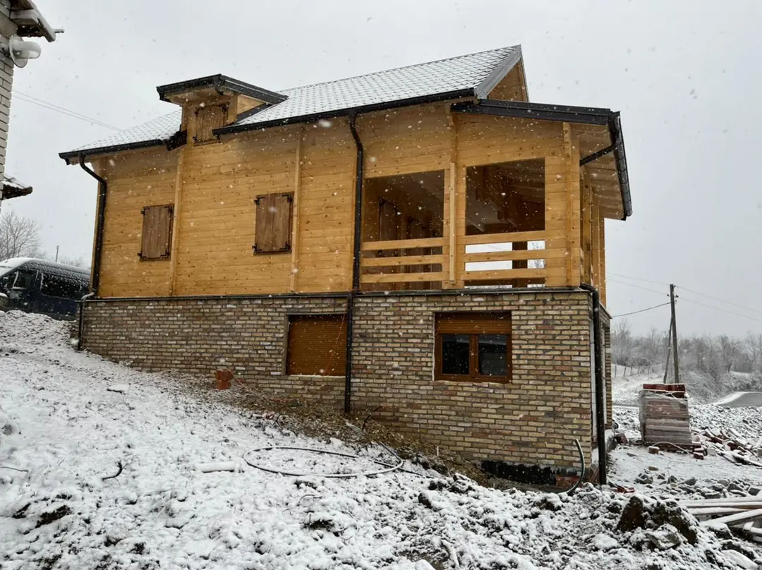 Timber upper floor of a log house above a masonry ground floor in the snow