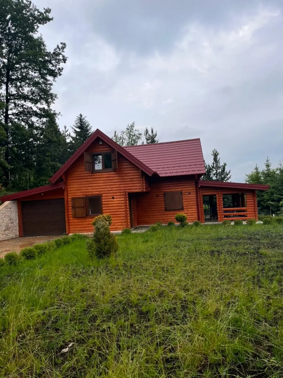 Log house with a red roof and garage
