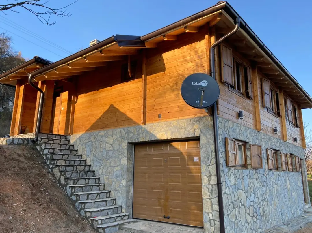 Log house on a stone ground floor with a garage and stairs on a slope