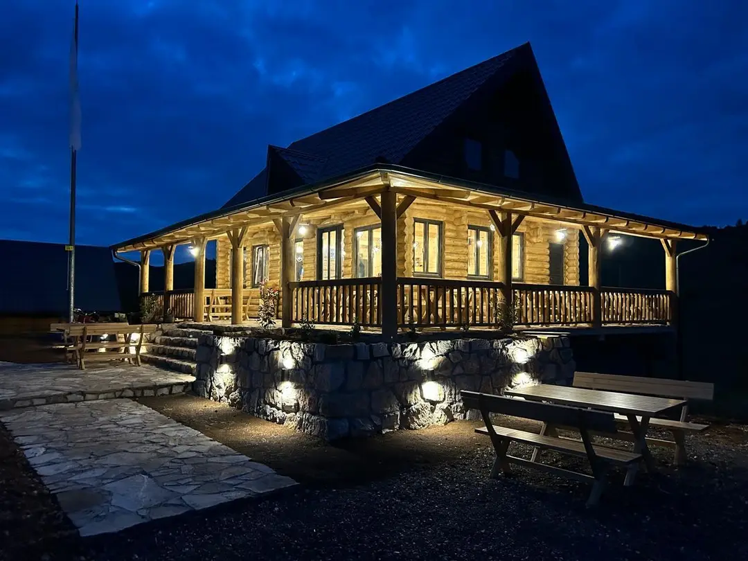 Log house with a wide porch lit at night