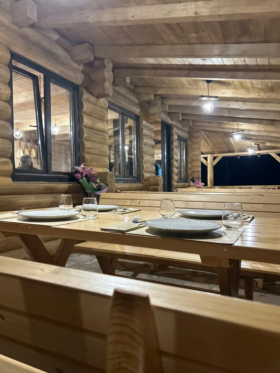 Trpezarija u brvnari sa dugačkim drvenim stolom i klupama