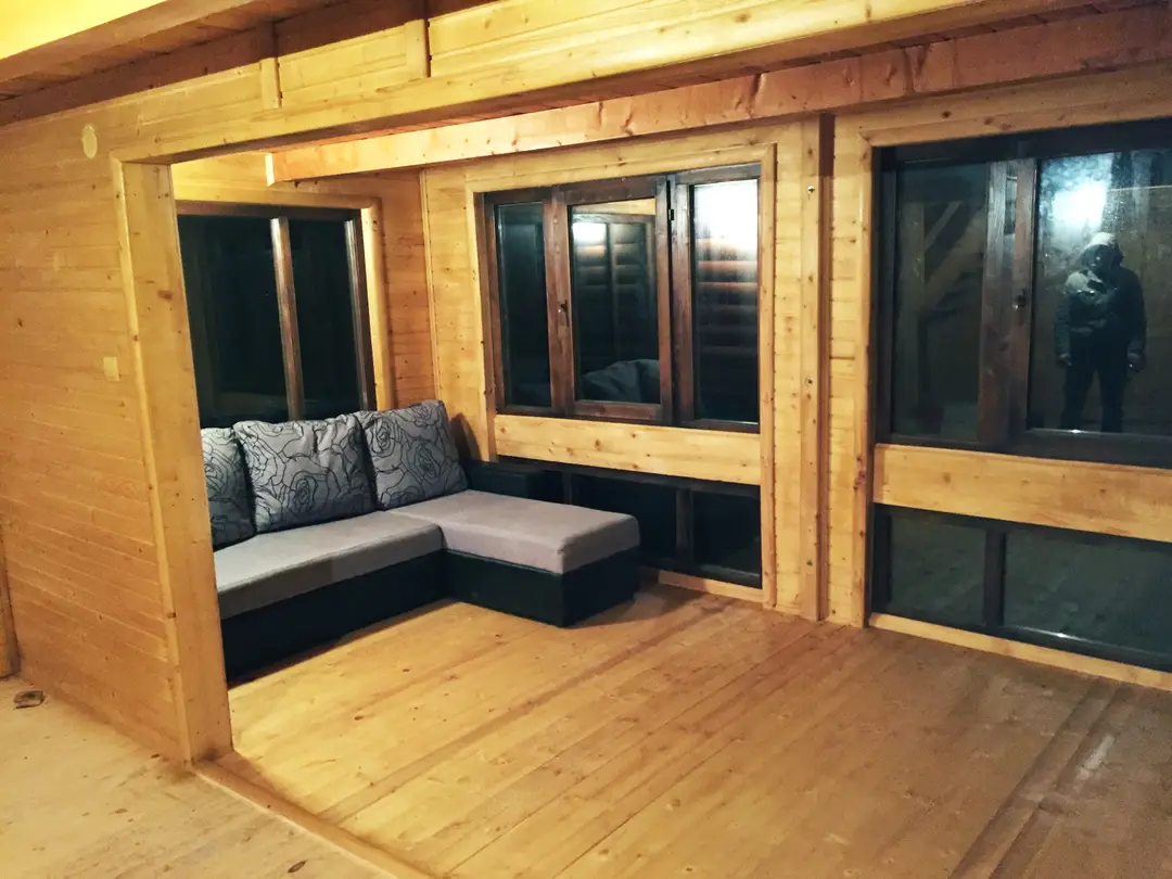 Interior of a timber building with a corner sofa and large windows