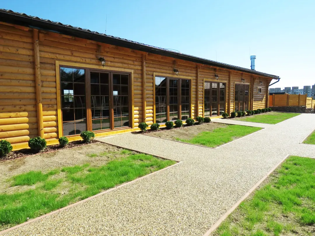 Long timber building with large windows and a gravel path