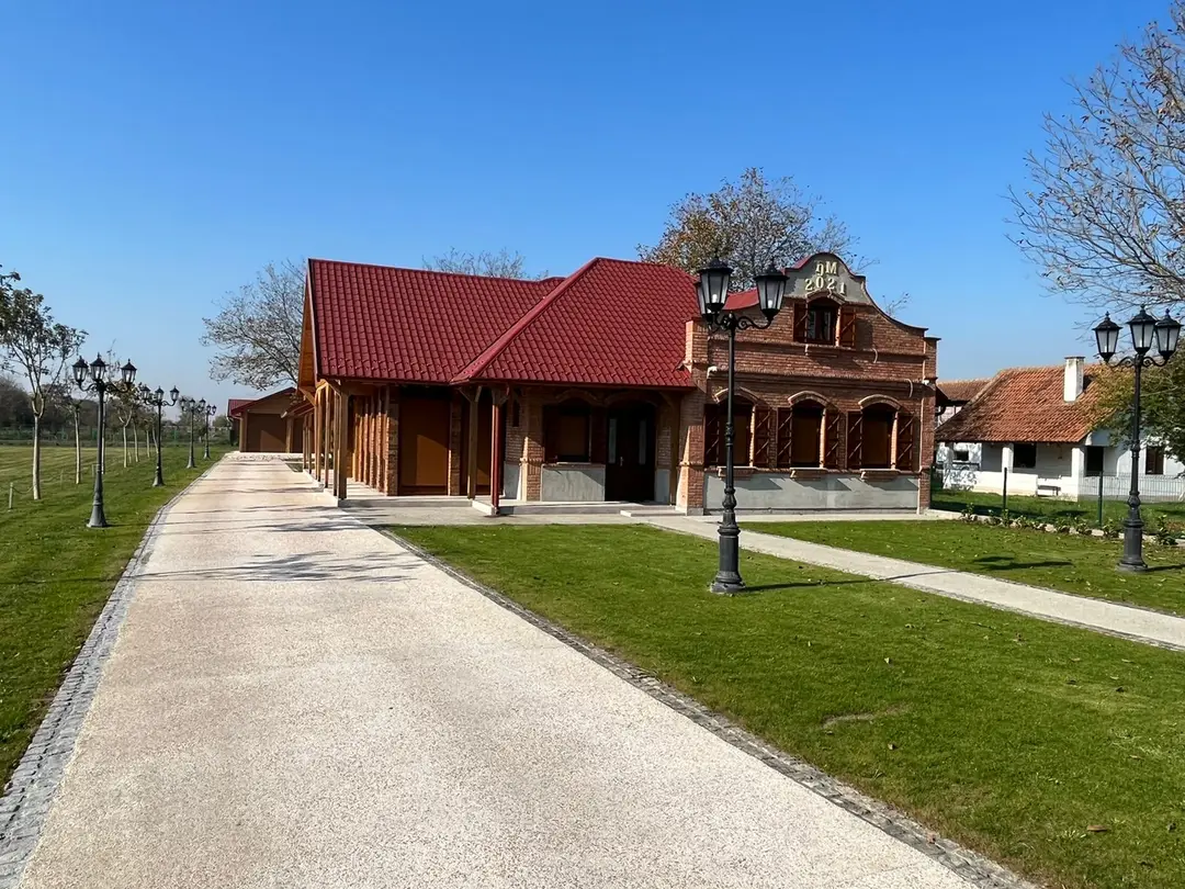 Log house with a red roof and a driveway lined with lanterns