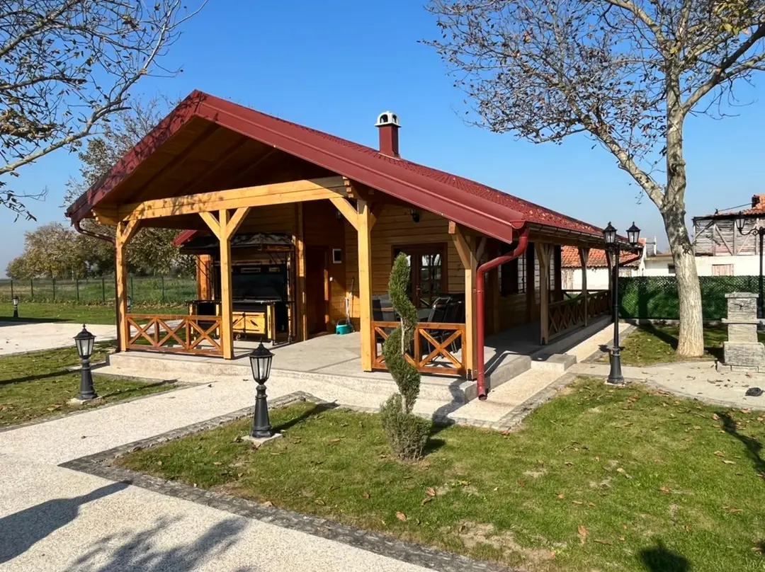 Log house with a covered porch and wooden railing in a landscaped garden