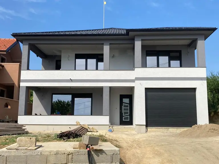 Two-storey prefab house with a garage and terraces, grey and white facade