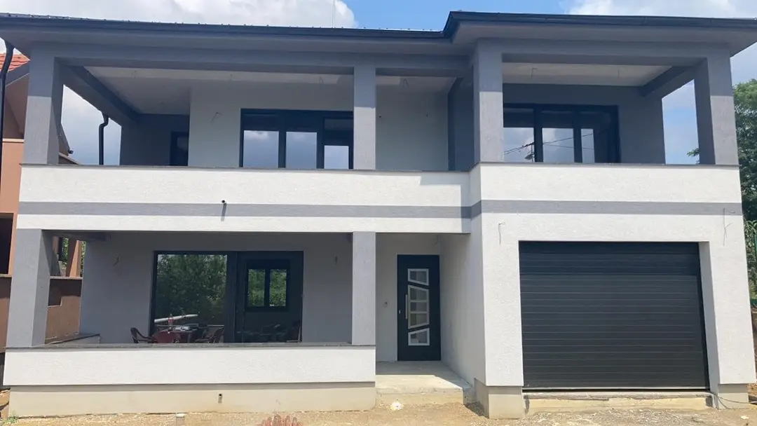 Facade of a two-storey house with terraces and dark window frames