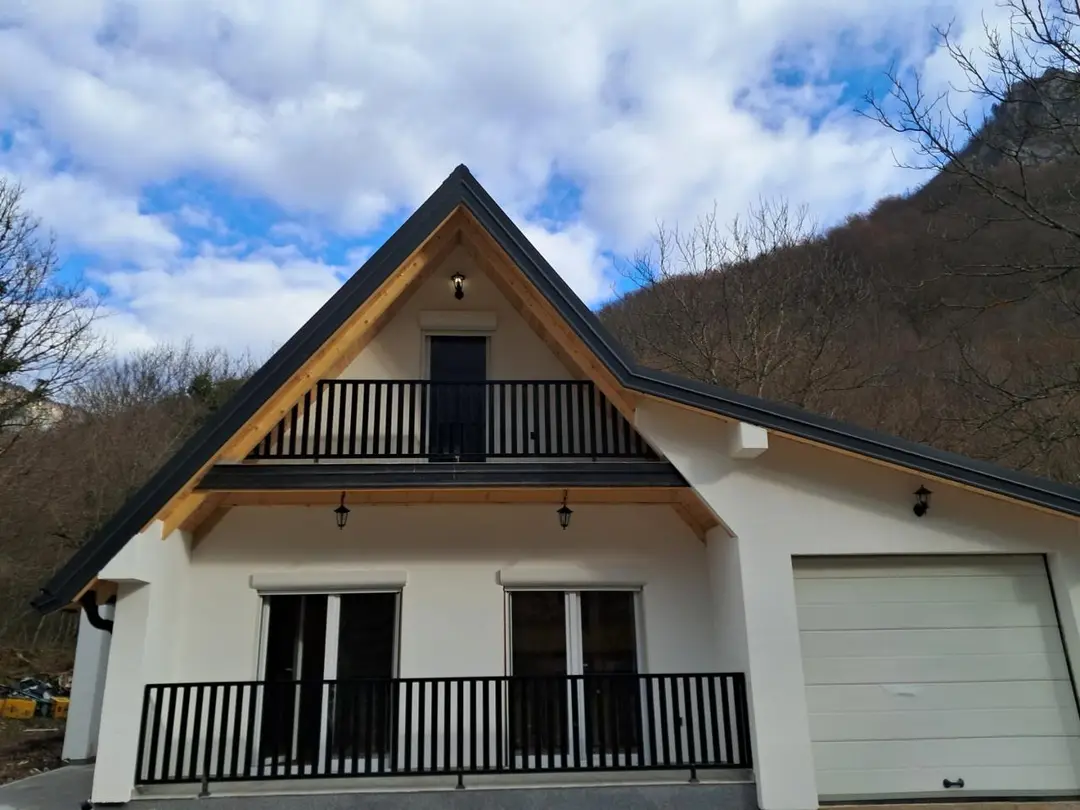Facade of a prefab house with an attic balcony and garage door