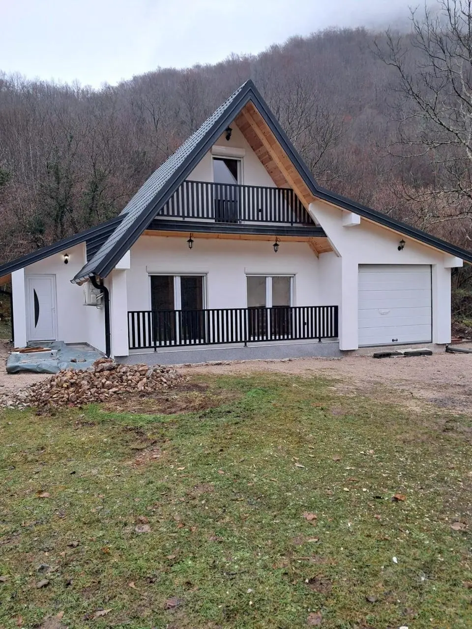 Prefab house with a garage on a plot below a wooded hill