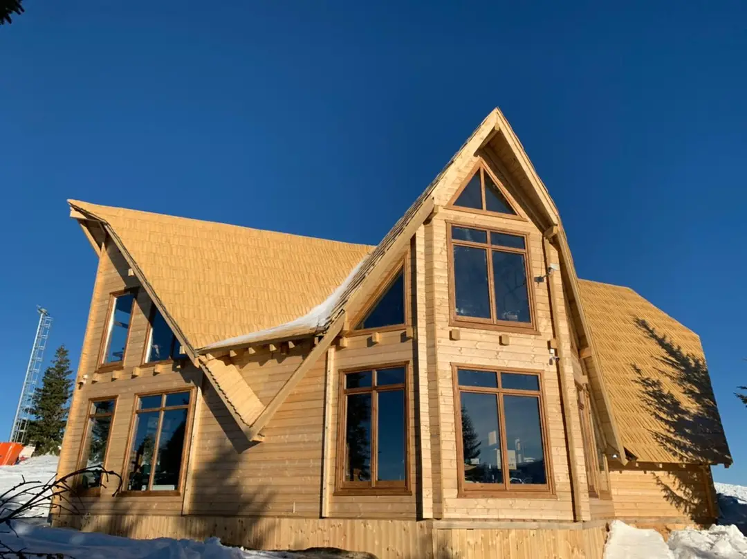 Wooden house with crossing gables and large glazed areas under a clear sky