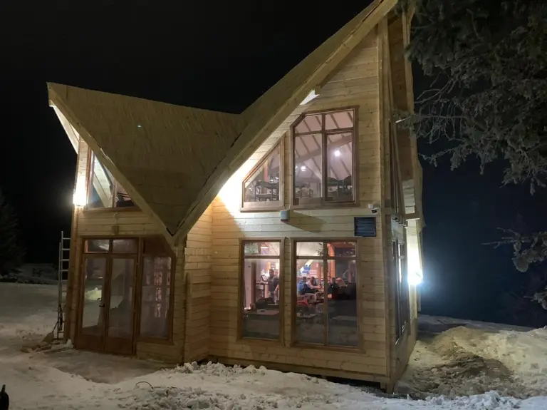 Wooden house with multiple gables lit at night