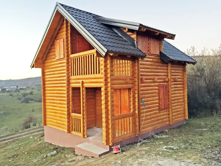 Mala brvnara na sprat sa drvenim balkonom na padini