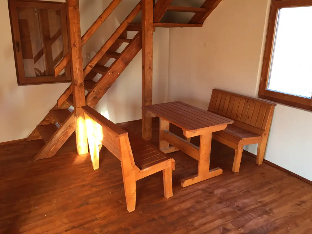 Wooden stairs, table and benches on the ground floor of a log house