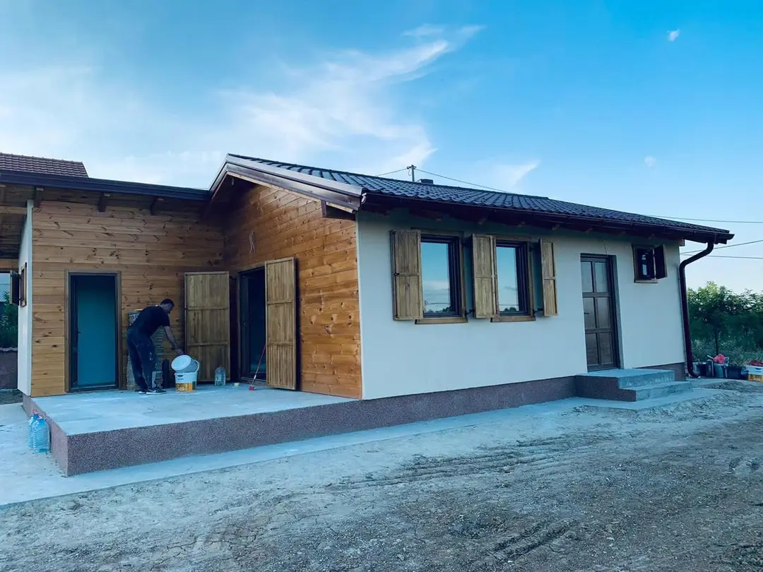 Small prefab house with white render and timber cladding near completion