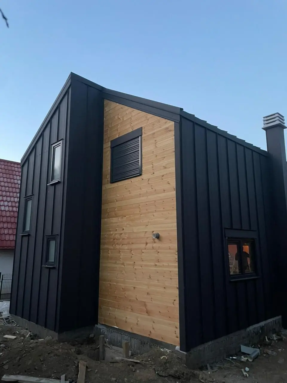Modern prefab house with a black metal facade and timber cladding