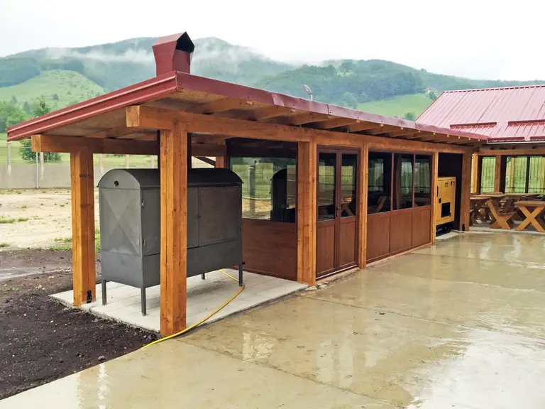 Covered wooden terrace with a large barbecue and red roof