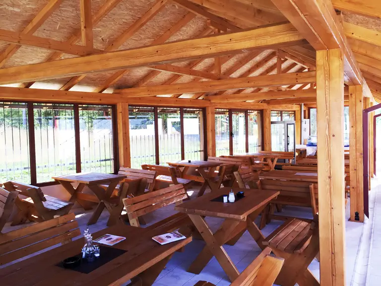 Inside a glazed wooden terrace with tables and benches