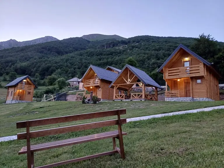 Naselje drvenih brvnara u planini, drvena klupa u prvom planu