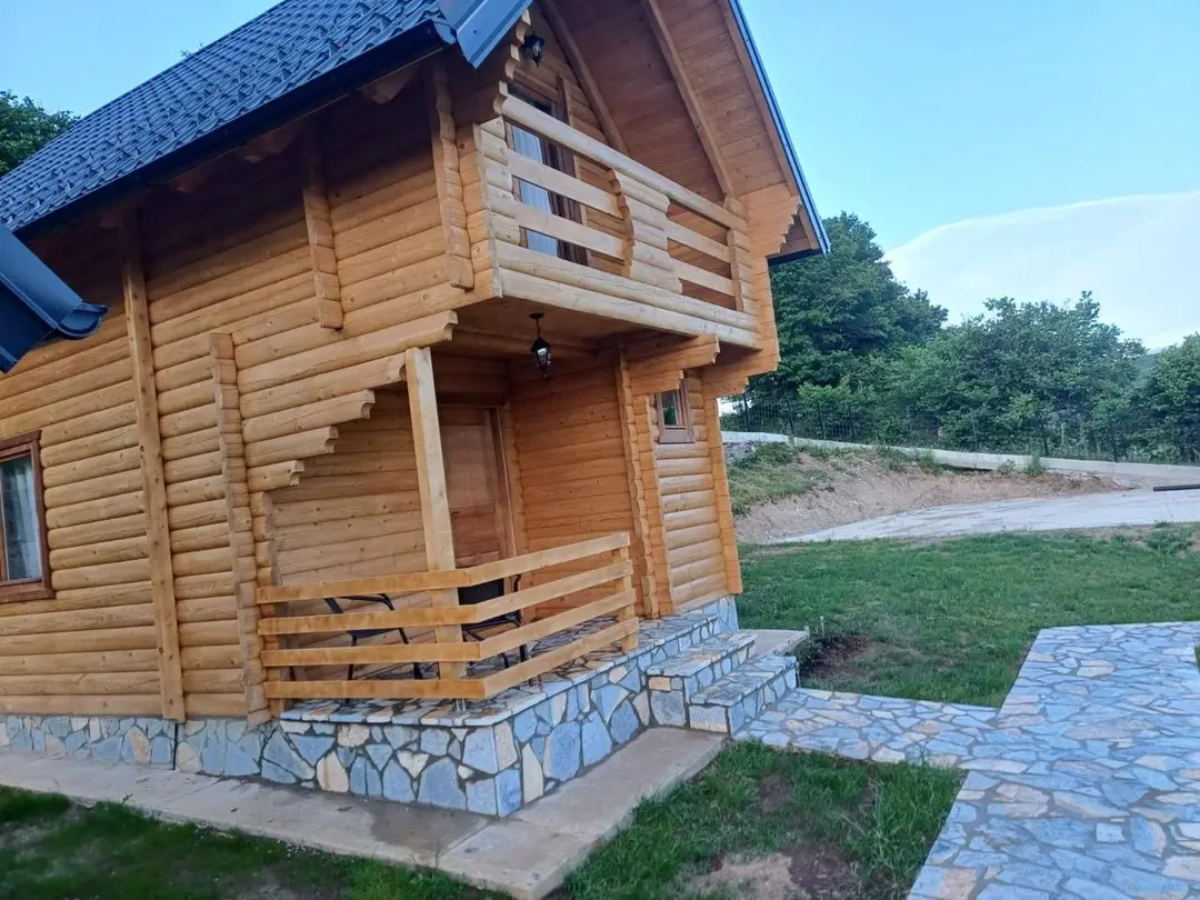 Corner of a log cabin with wooden stairs and a balcony