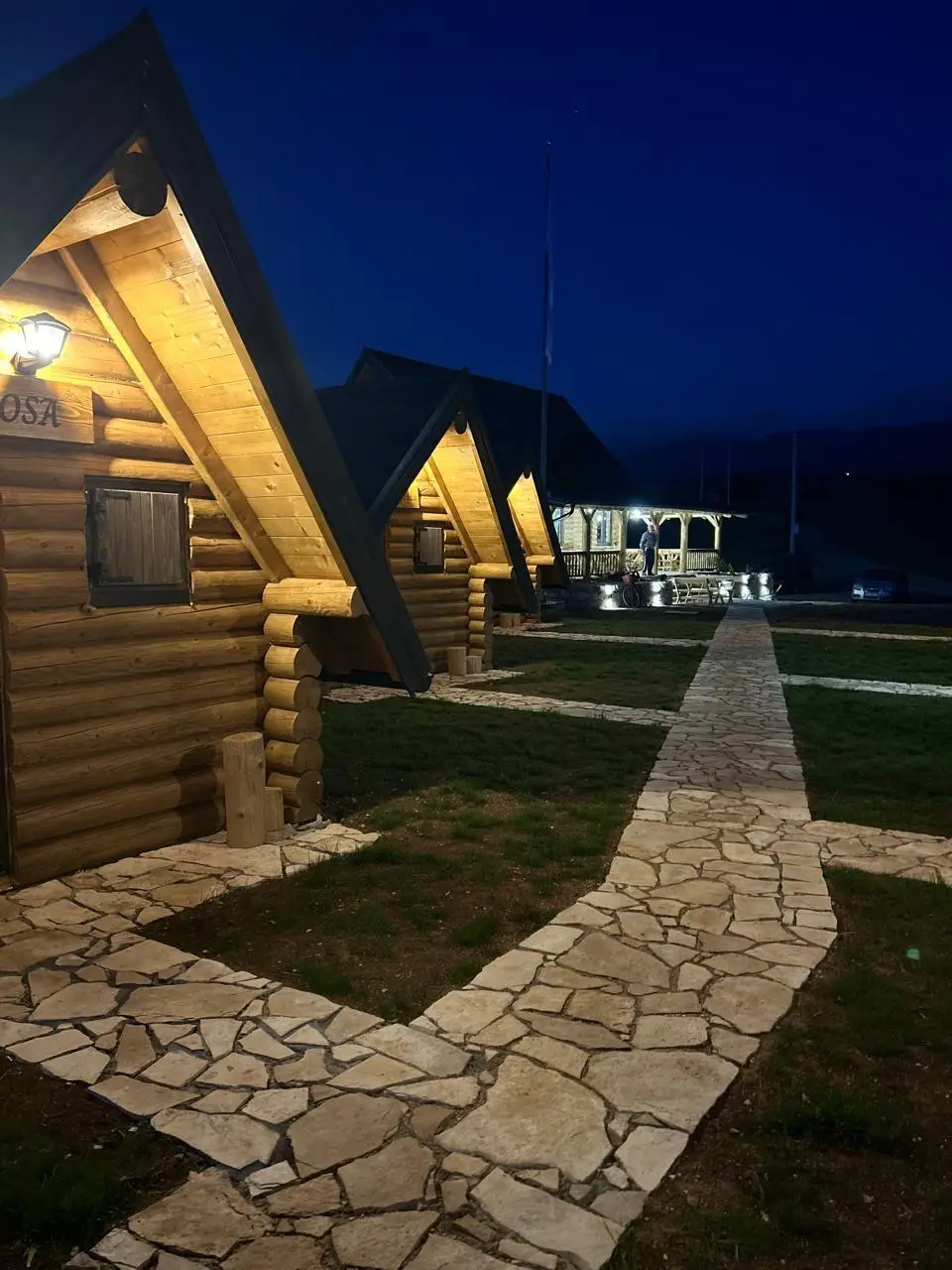 Lit log cabins and a stone path at night