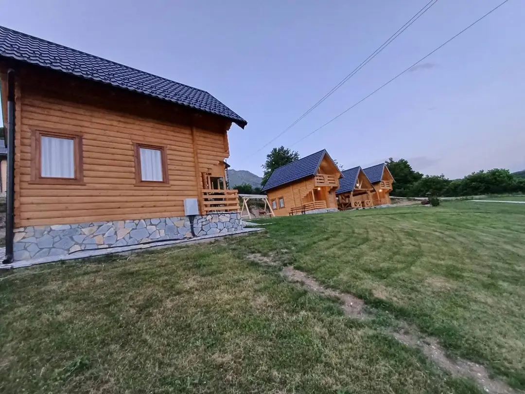 Log cabin on a stone base, with a row of cabins behind it
