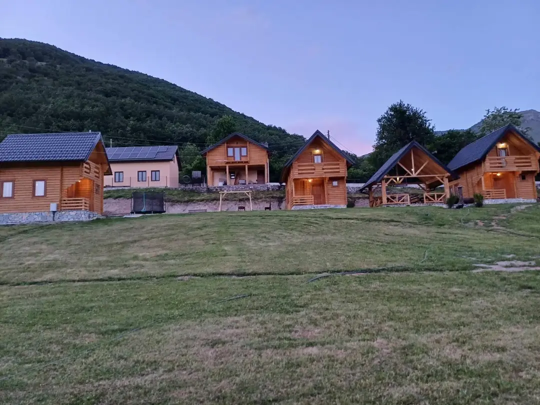 Row of two-storey log cabins on a mountain meadow at dusk