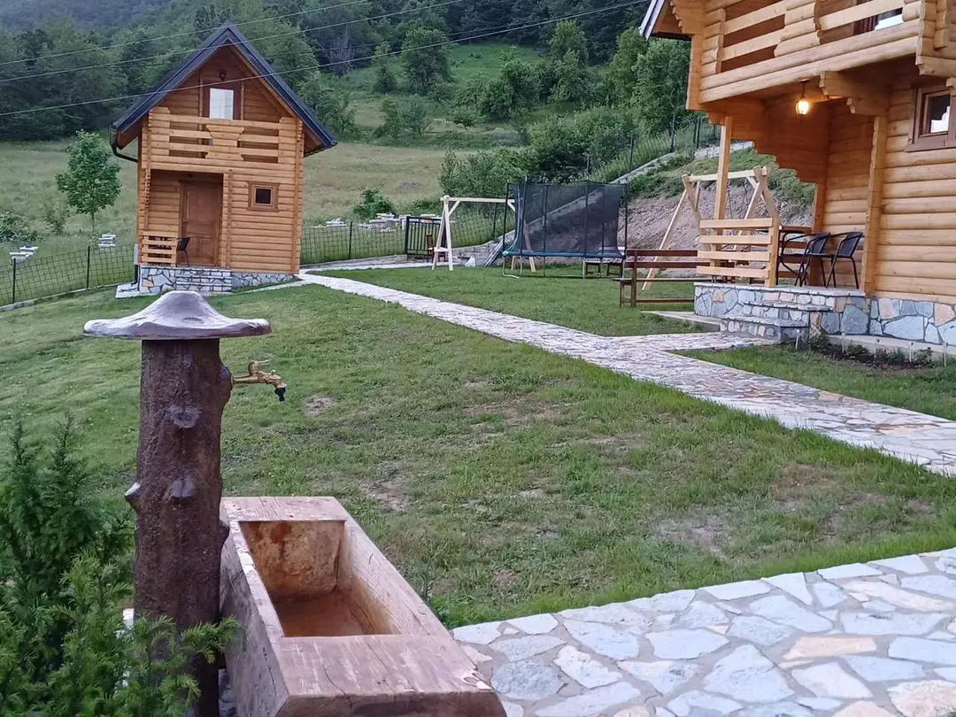 Stone path and a wooden water fountain in front of the cabins