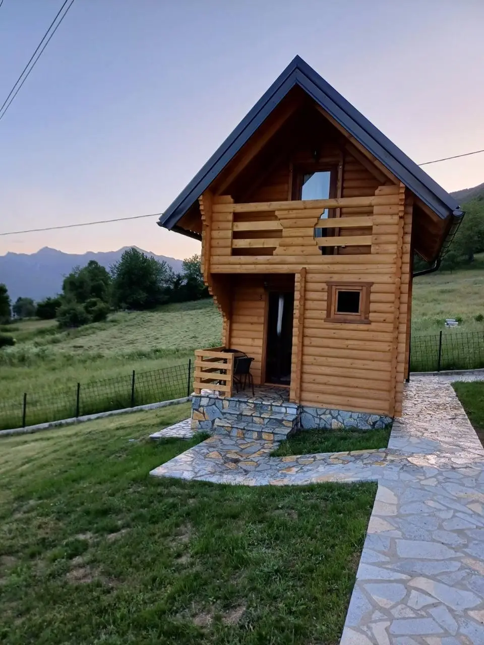 Small two-storey log cabin with a wooden balcony