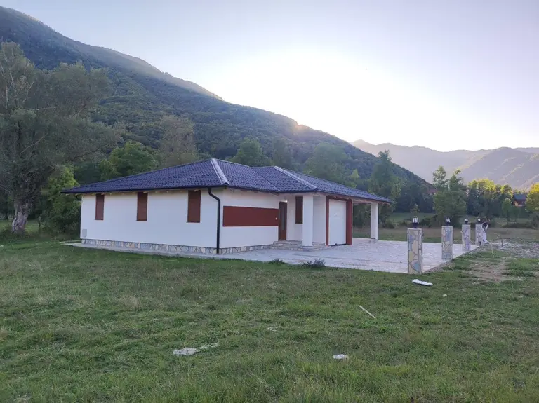 Single-storey prefab house with a garage in a valley below a mountain