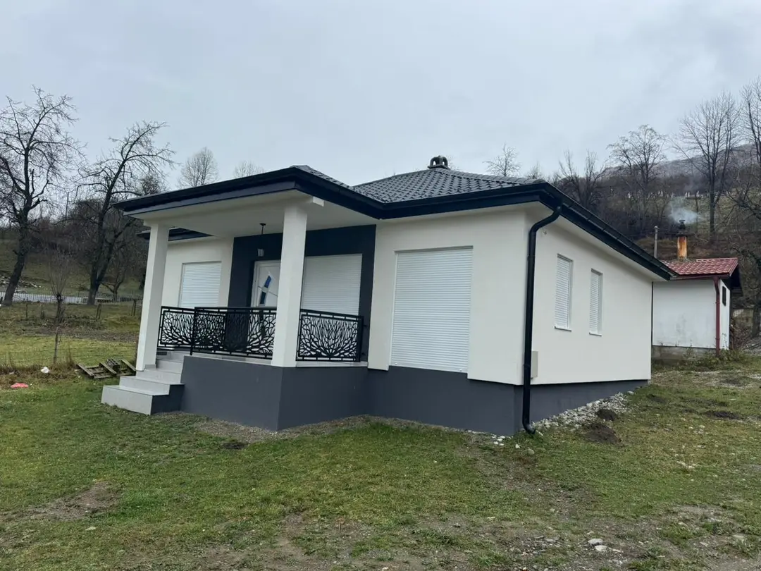 Single-storey prefab house with a porch, white columns and wrought iron railing