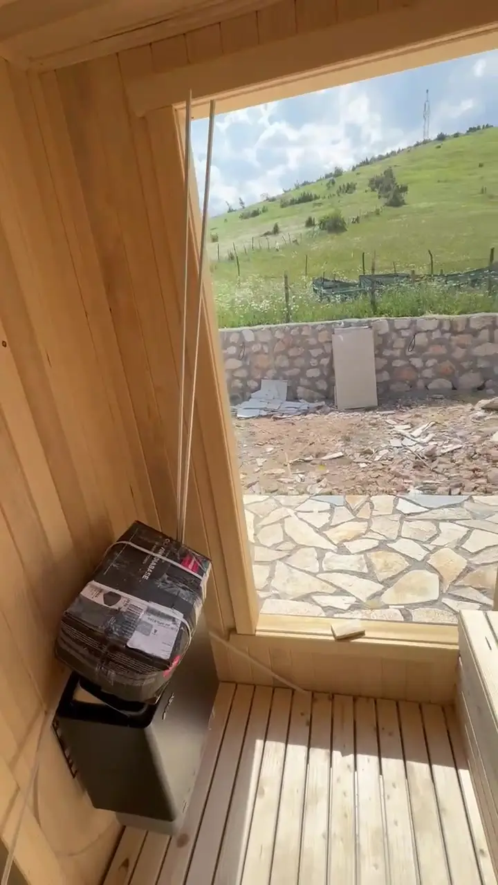 Unutrašnjost drvene saune sa grijačem i prozorom prema planini