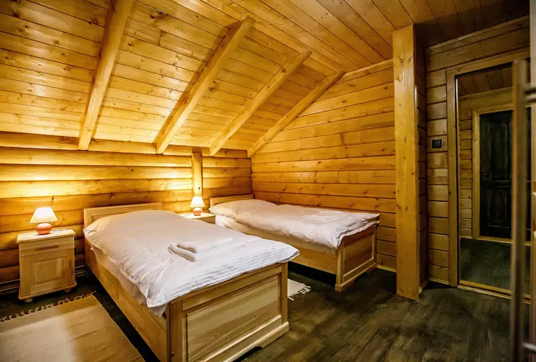 Bedroom in a log house with two beds and wooden furniture